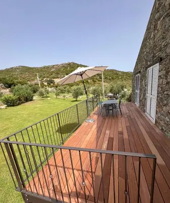 a wooden deck with a table and an umbrella at Maison enchanteresse à Santo-Pietro-di-Tenda avec jacuzzi in Santo-Pietro-di-Tenda