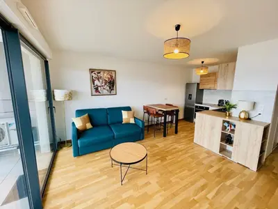 a living room with a blue couch and a table at Ajaccio T2 grand standing neuf vue mer centre-ville & plages in Ajaccio