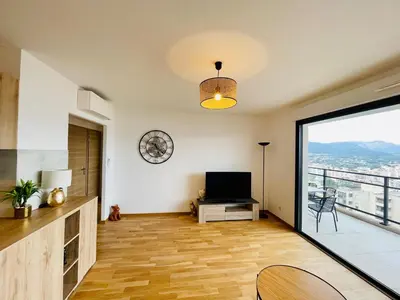 a living room with a television and a large window at Ajaccio T2 grand standing neuf vue mer centre-ville & plages in Ajaccio