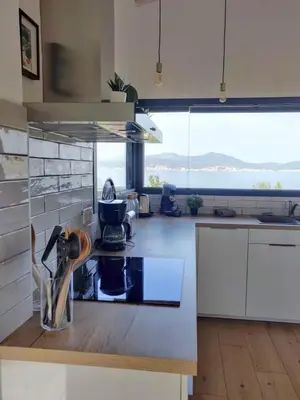 a kitchen with white cabinets and a large window at Villa ARIA, piscine, vue mer 120 m2 tout confort - 4 personnes in Pietrosella