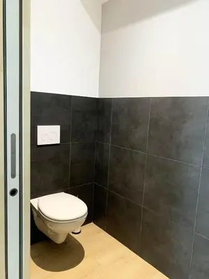 a bathroom with a white toilet and black tiles at Villa ARIA, piscine, vue mer 120 m2 tout confort - 4 personnes in Pietrosella