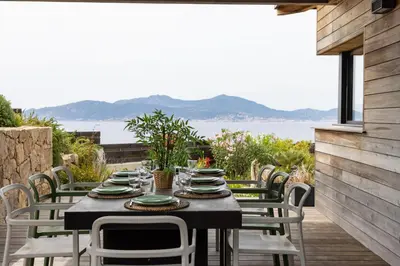 a table and chairs on a patio with a view of the water at Villa ARIA, piscine, vue mer 120 m2 tout confort - 4 personnes in Pietrosella