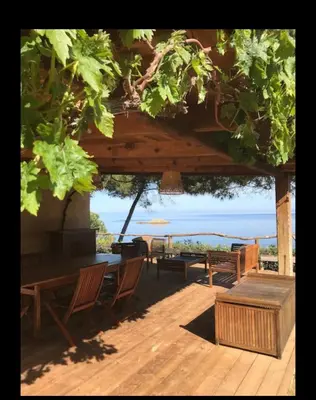 a patio with benches and a table and a view of the ocean at Villa Terra Casanova pieds dans l'eau à 20 mn d Ajaccio in Villanova