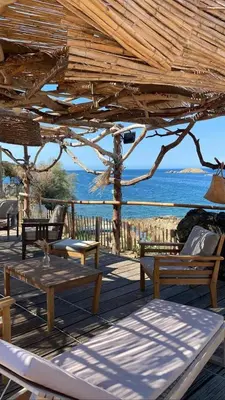 a wooden deck with a table and chairs and the ocean at Villa Terra Casanova pieds dans l'eau à 20 mn d Ajaccio in Villanova