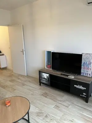 a living room with a flat screen tv and a table at SUPERBE APPARTEMENT FACE AUX ILES SANGUINAIRES in Ajaccio
