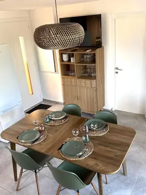 a dining room with a wooden table and chairs at Résidence hôtelière les hameaux de saint cyprien appartement 2 chambres in Lecci