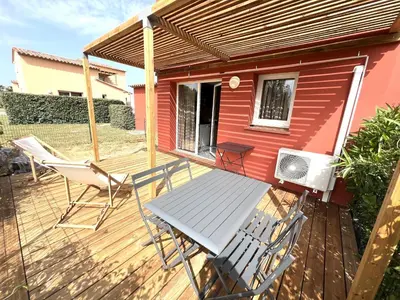 a deck with a picnic table and chairs on it at Résidence hôtelière les hameaux de saint cyprien appartement 35 M2 1 chambre in Lecci