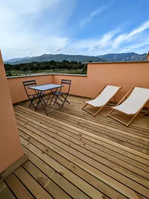 a patio with two chairs and a table on a deck at Résidence hôtelière les hameaux de saint cyprien appartement 35 M2 1 chambre in Lecci