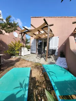 a patio with a table and chairs under an umbrella at MINI VILLA A 5MIN À PIEDS DE LA PLAGE SANTA GIULIA in Porto-Vecchio