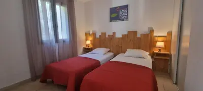 two beds in a hotel room with red sheets at Vos vacances à Lama France Corse in Lama