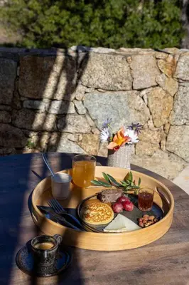a patio with couches and tables and a stone wall at Domaine du Reginu in Santa-Reparata-di-Balagna