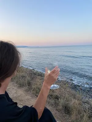 a woman holding a drink in front of the ocean at La Casetta Prunete in Cervione