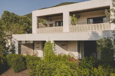 an apartment building with a balcony with chairs at VILLA FLAKA Boutique Hôtel Wellness in Cargèse