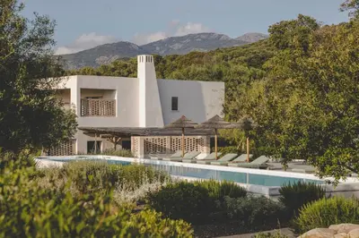 a house with a swimming pool next to a mountain at VILLA FLAKA Boutique Hôtel Wellness in Cargèse