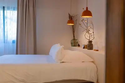 a bedroom with a bed with white sheets and a window at VILLA FLAKA Boutique Hôtel Wellness in Cargèse