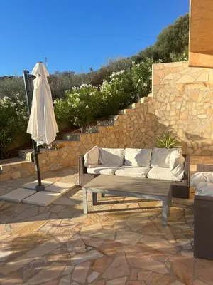 a couch sitting on a patio next to a stone wall at Modern villa 5 double bedrooms, new AC, private pool and stunning view 800 m from beach in Sagone