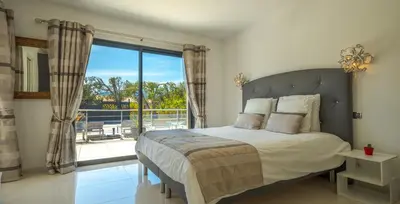 a bedroom with a bed and a large window at Villa Les Arbousiers - Piscine Chauffée Sécurisée - 210m2 - 4 Suites in Porto-Vecchio