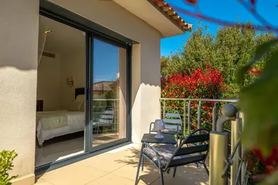 a room with a balcony with a bed and a bedroom at Villa Les Arbousiers - Piscine Chauffée Sécurisée - 210m2 - 4 Suites in Porto-Vecchio