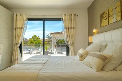 a bedroom with a large bed and a balcony at Villa Les Arbousiers - Piscine Chauffée Sécurisée - 210m2 - 4 Suites in Porto-Vecchio