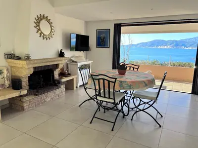 a dining room with a table and chairs and a fireplace at Les Terrasses du Pano - 95 m2 au calme - Jardin - Barbecue - Transats - Pleine vue mer - Wifi Fibre in Porticcio