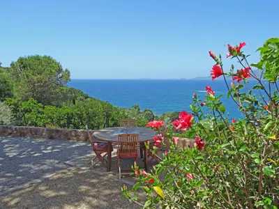 a table and chairs with the ocean in the background at Les Terrasses du Pano - 95 m2 au calme - Jardin - Barbecue - Transats - Pleine vue mer - Wifi Fibre in Porticcio