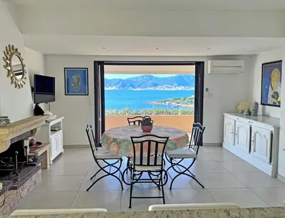 a dining room with a table and a view of the ocean at Les Terrasses du Pano - 95 m2 au calme - Jardin - Barbecue - Transats - Pleine vue mer - Wifi Fibre in Porticcio
