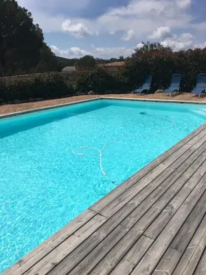 a large blue swimming pool with a wooden deck at Appartement proche des plus belles plages in Porto-Vecchio