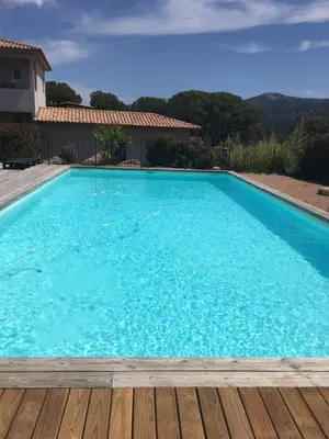 a large blue swimming pool with a wooden deck at Appartement proche des plus belles plages in Porto-Vecchio