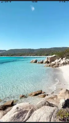 a beach with blue water and rocks on the shore at Appartement proche des plus belles plages in Porto-Vecchio