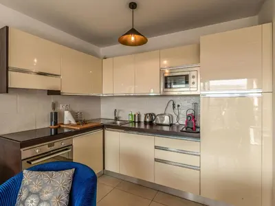 a kitchen with white cabinets and a blue chair at Apartment Cita Di Sali 13 by Interhome in Porto-Vecchio