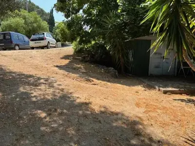 a dirt yard with two cars parked next to a building at Maison de charme à Ajaccio avec terrasse et jardin in Ajaccio