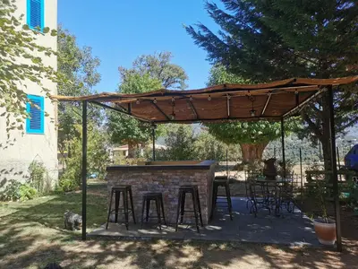 a patio with a table and stools under a wooden umbrella at Casa Maria in Vico