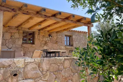 a stone house with a wooden pergola at Casetta Soli Di Santa Lucia in Sainte-Lucie de Porto-Vecchio