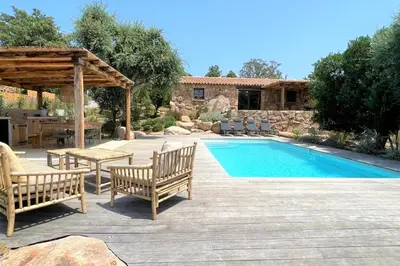 a swimming pool with two chairs and a table and a pavilion at Casetta Soli Di Santa Lucia in Sainte-Lucie de Porto-Vecchio
