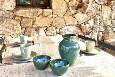 a table with a green vase and bowls on it at Casetta Soli Di Santa Lucia in Sainte-Lucie de Porto-Vecchio