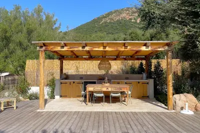 a wooden pergola with a table and chairs on a deck at Casetta Soli Di Santa Lucia in Sainte-Lucie de Porto-Vecchio
