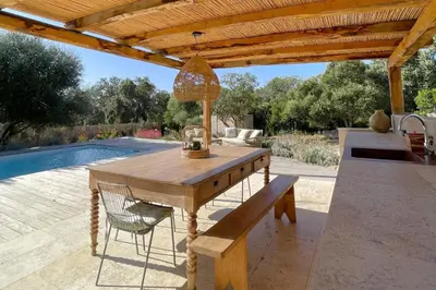 a wooden table and a bench under a wooden pergola at Casetta Soli Di Santa Lucia in Sainte-Lucie de Porto-Vecchio
