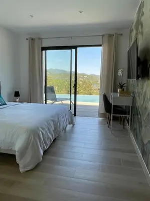 a bedroom with a bed and a desk with a view at Villa neuve avec grande piscine chauffée vue mer in Conca