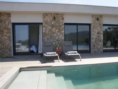 two chairs and a swimming pool in front of a house at Villa neuve avec grande piscine chauffée vue mer in Conca