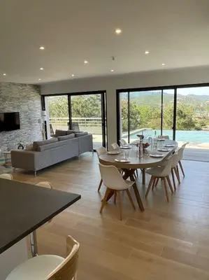 a living room with a table and chairs and a couch at Villa neuve avec grande piscine chauffée vue mer in Conca