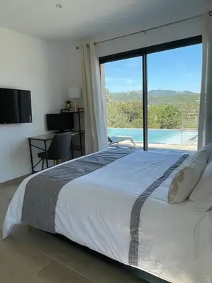 a bedroom with a large bed and a large window at Villa neuve avec grande piscine chauffée vue mer in Conca