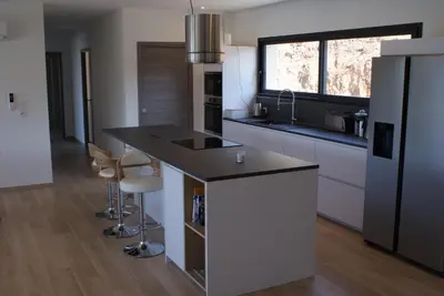 a kitchen with a island with a counter and stools at Villa neuve avec grande piscine chauffée vue mer in Conca