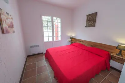 a bedroom with a red bed and a window at Maisons Jumelées in Piana