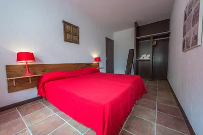 a bedroom with a red bed and a red lamp at Maisons Jumelées in Piana
