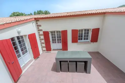 a building with red doors and a bench on a patio at Maisons Jumelées in Piana