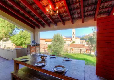 a table on a patio with a large window at Maisons Jumelées in Piana