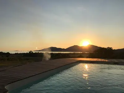 a swimming pool with a sunset in the background at VILLA SANTONI in Porticcio