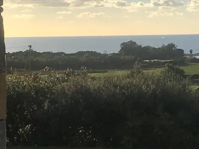 a field of grass with the ocean in the background at VILLA SANTONI in Porticcio