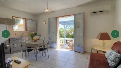 a living room with a table and a kitchen with a view at L'AMANDIER -LE FIGUIER-LES LAURIERS ROSES in Ajaccio