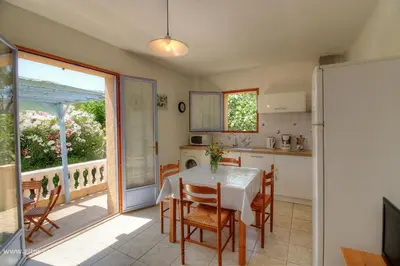 a kitchen and dining room with a table and chairs at L'AMANDIER -LE FIGUIER-LES LAURIERS ROSES in Ajaccio